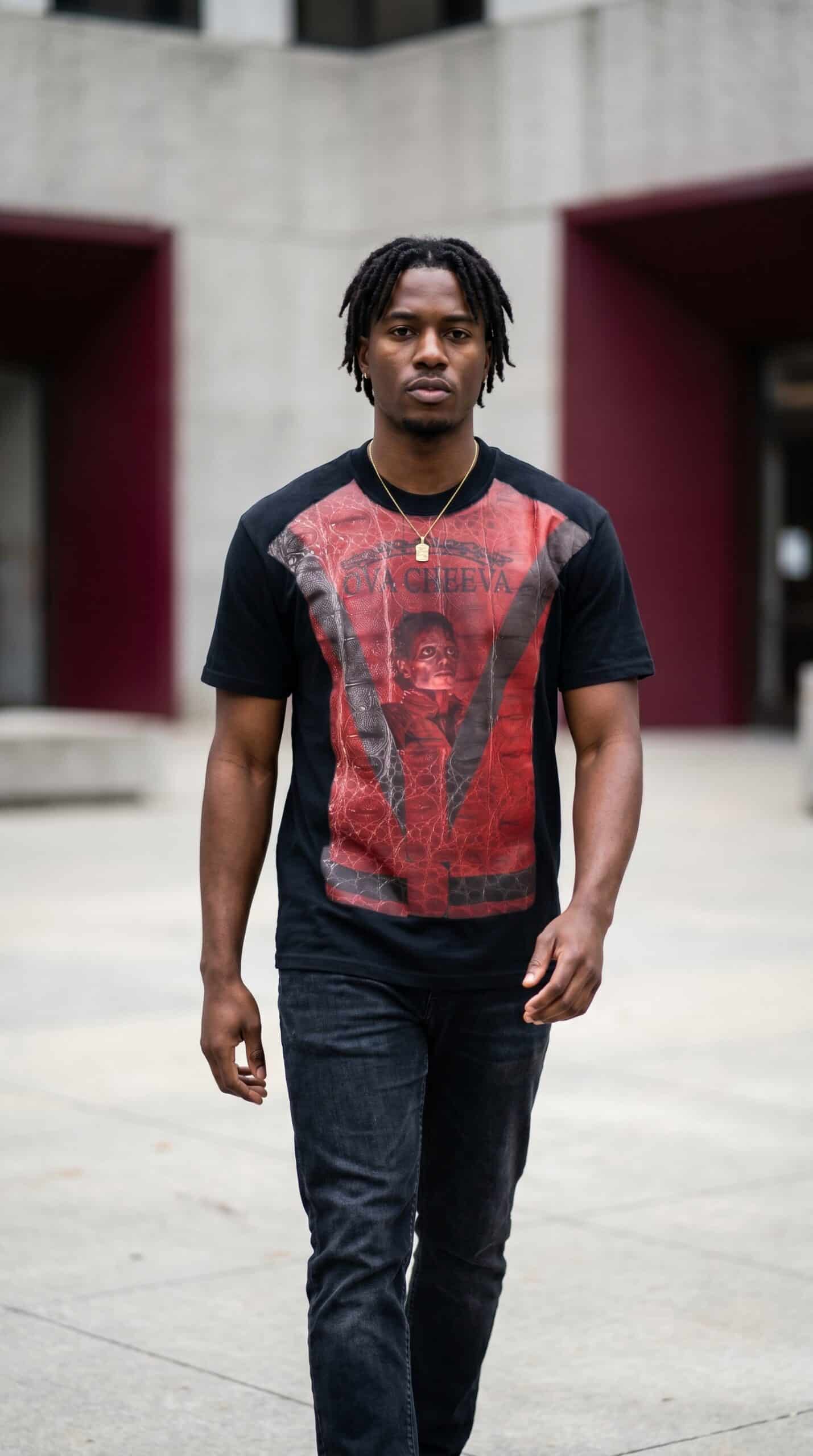 Young man wearing urban streetwear with graphic T-shirt in an outdoor city setting.