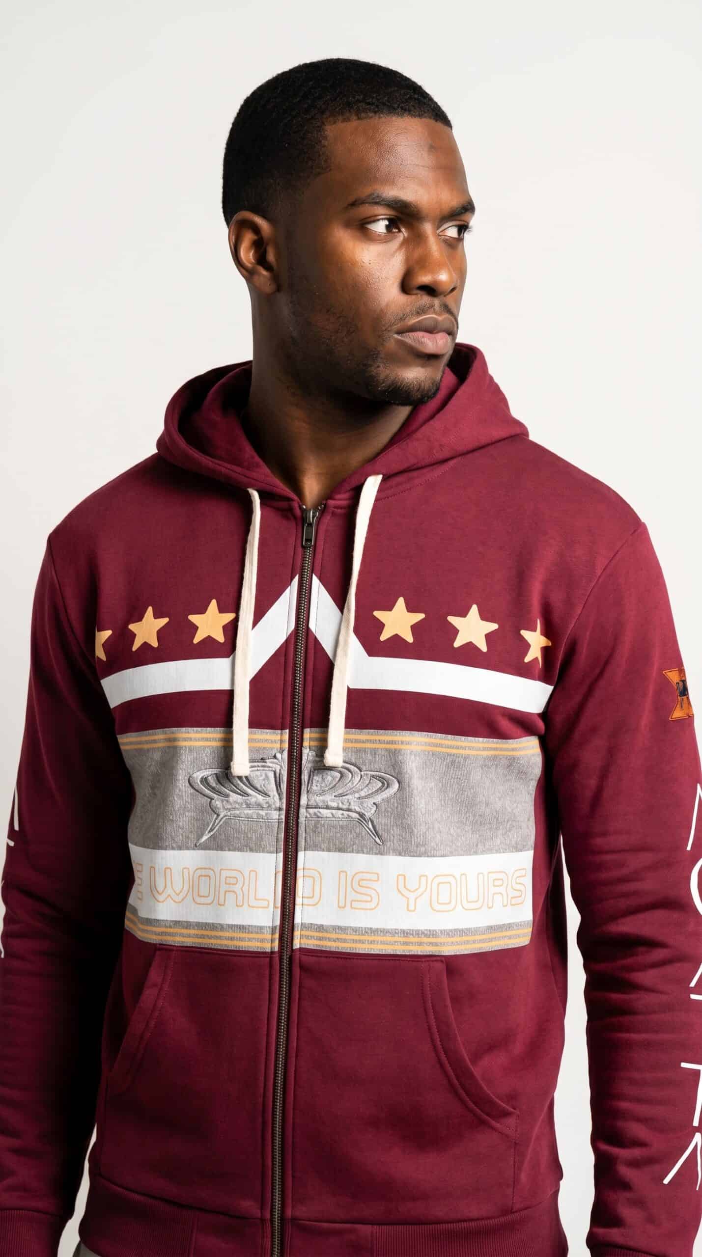 A man wearing a maroon hoodie with bold graphic design and stars, representing urban culture and sty.
