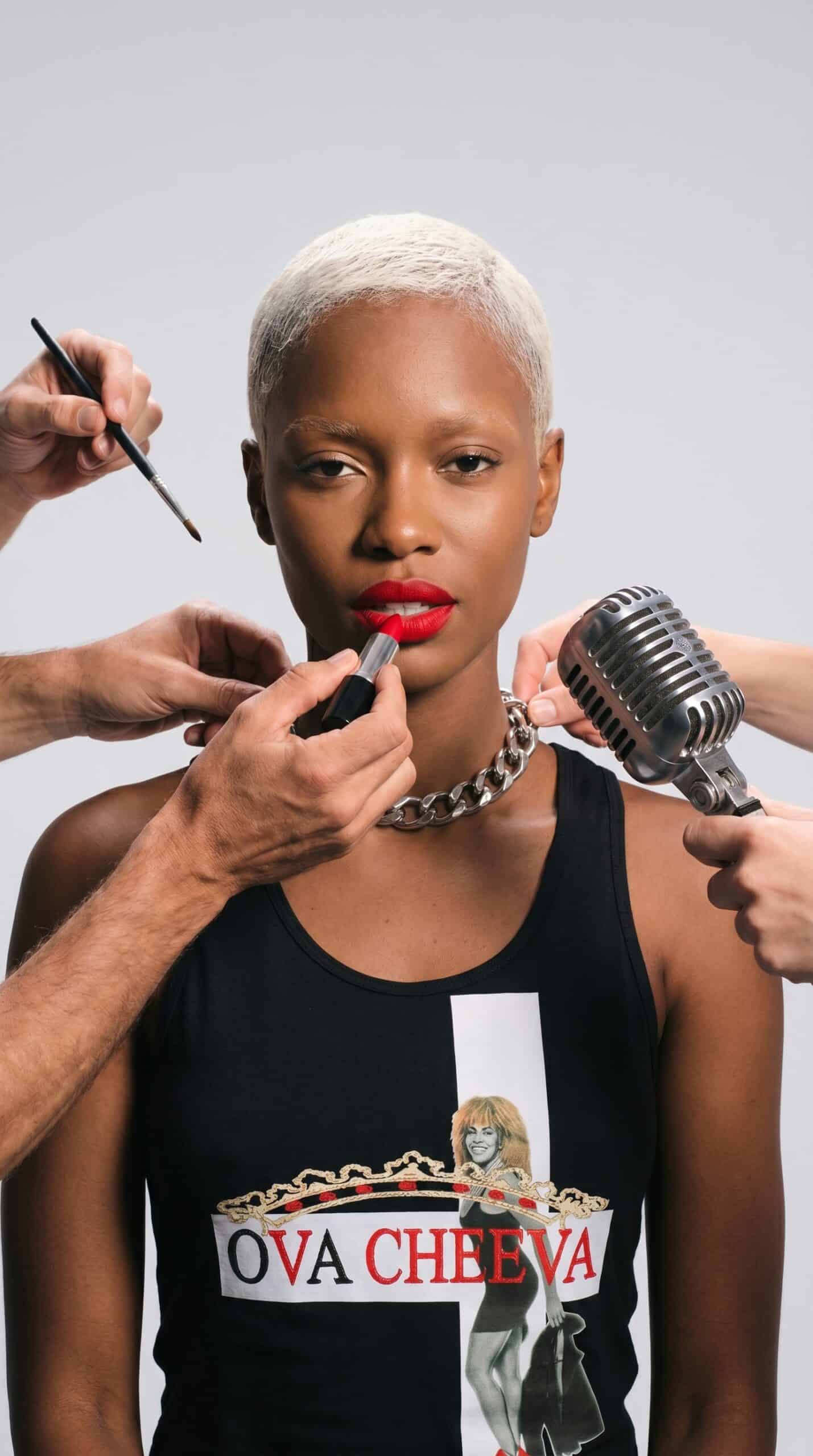 Bold woman with short platinum blonde hair getting makeup applied, urban style.