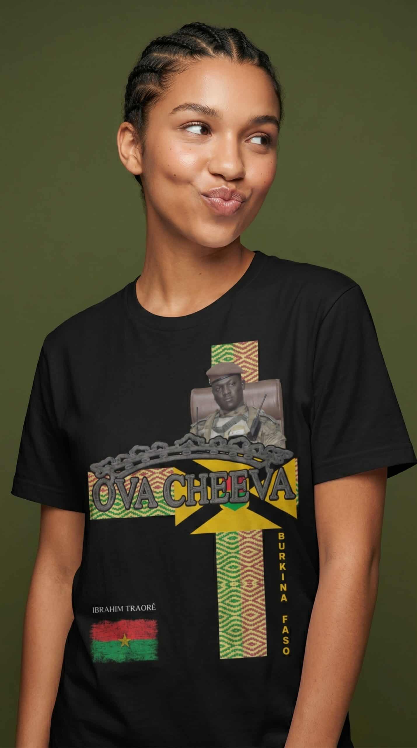 A woman wearing a black T-shirt with colorful graphic design and text, standing against a green back.