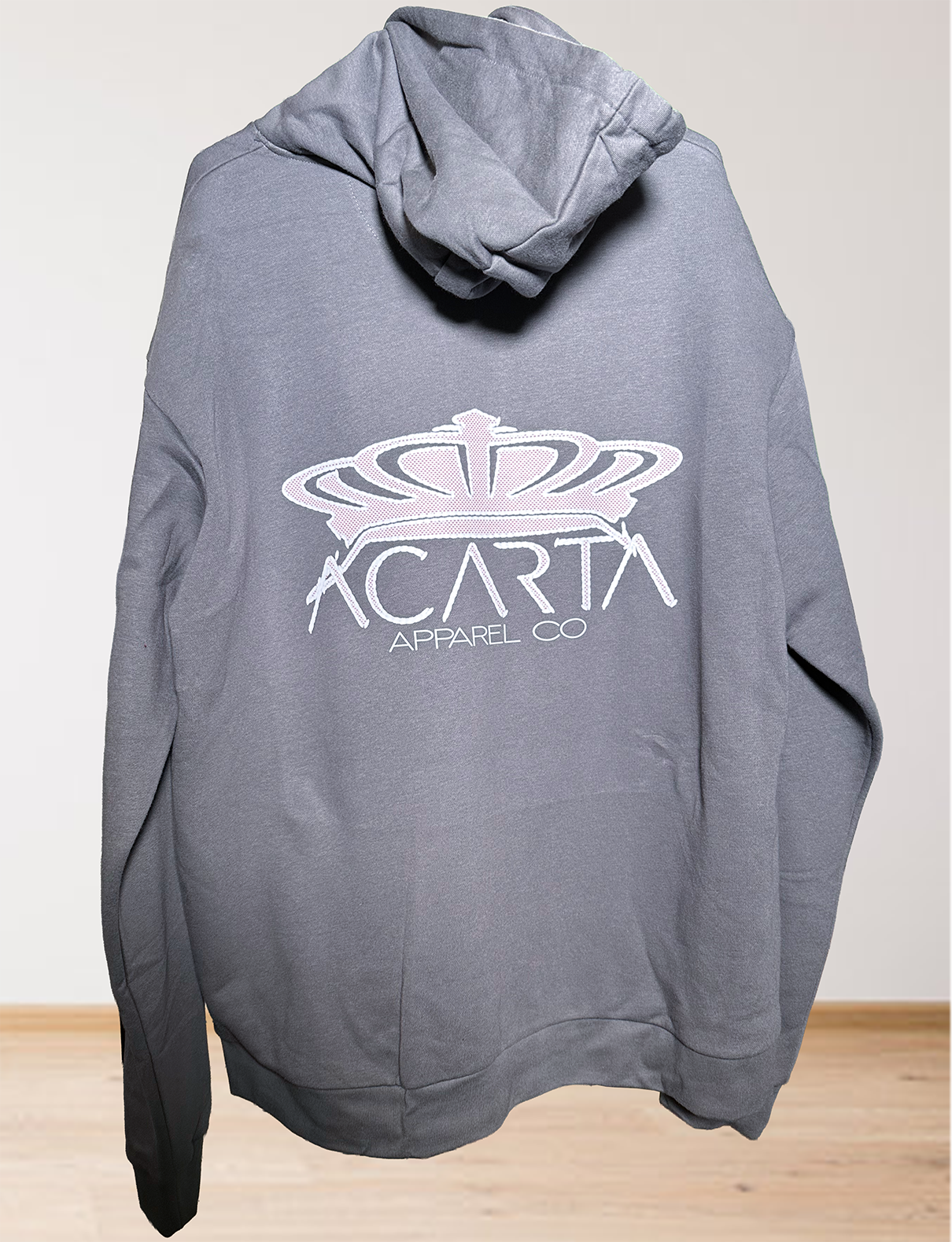 The Mens Adult Heavy Metal The World Is Yours Zip Hoodie features a gray design with a white crown graphic and ACARTA APPAREL CO text on the back, shown against a simple indoor backdrop.