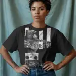 A woman with short curly hair stands with hands on hips, wearing the OVA CHEEVA Women's Cotton L.L. Cool J. Graphic T-Shirt—black with a woman and boombox design, white stripes, chains, and "OVACHEEVA" text—paired with blue jeans. Pale blue background.