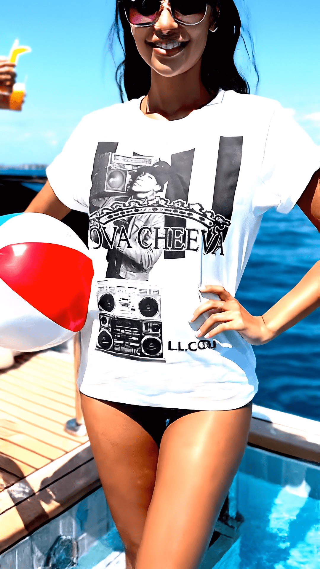 Woman in white Too Dapper t-shirt holding a beach ball by the pool.