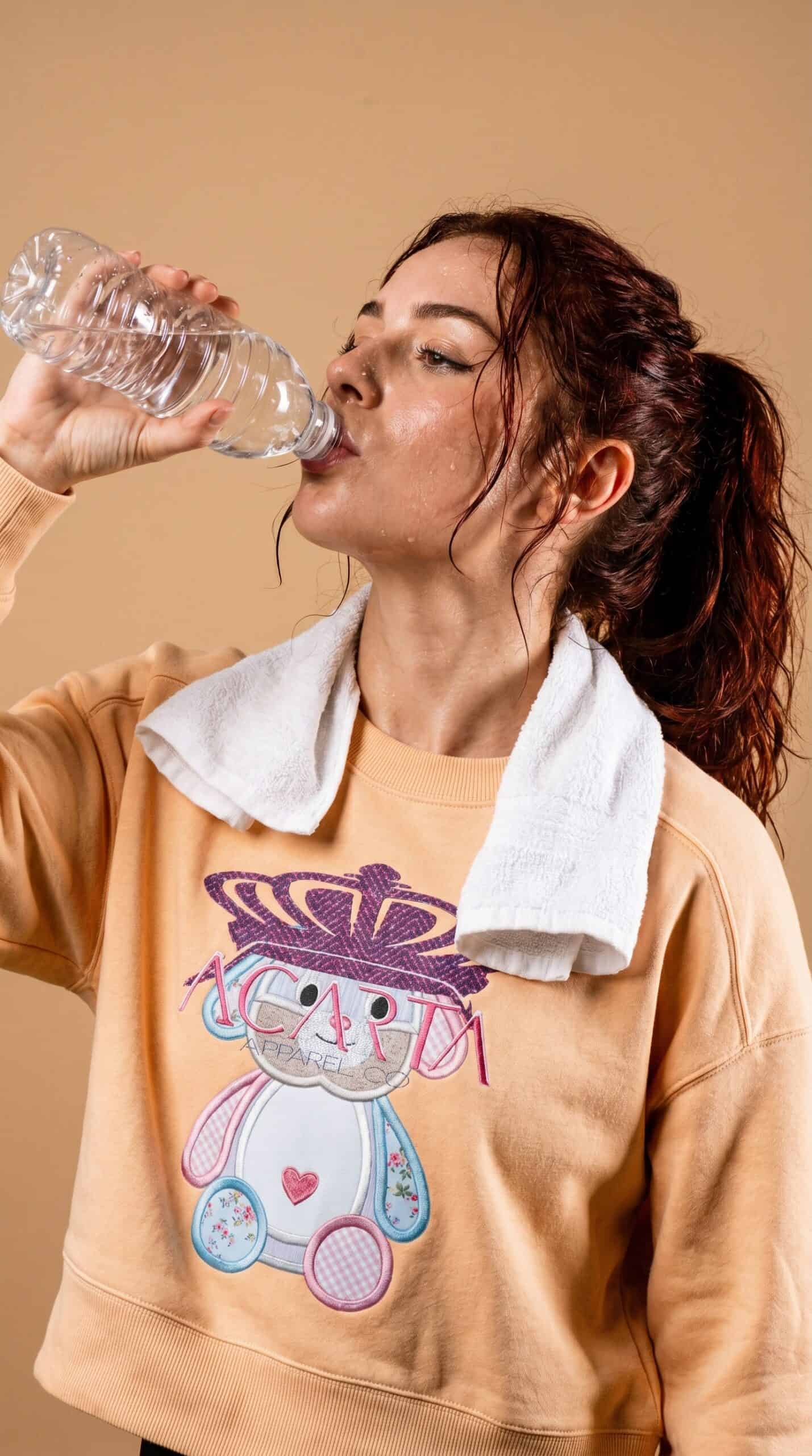 A woman drinking water, casual urban style, indoor setting.