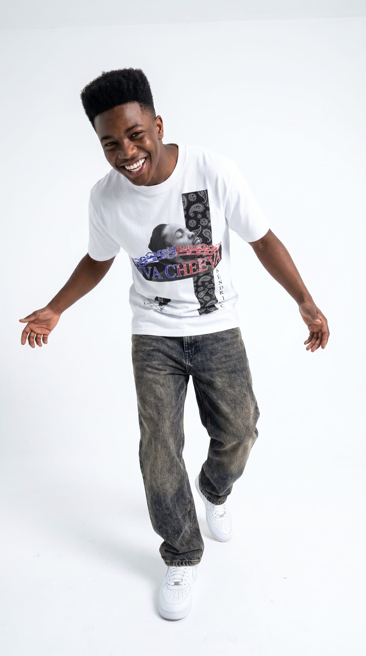 A young man smiling and dancing in casual urban apparel against a white background.