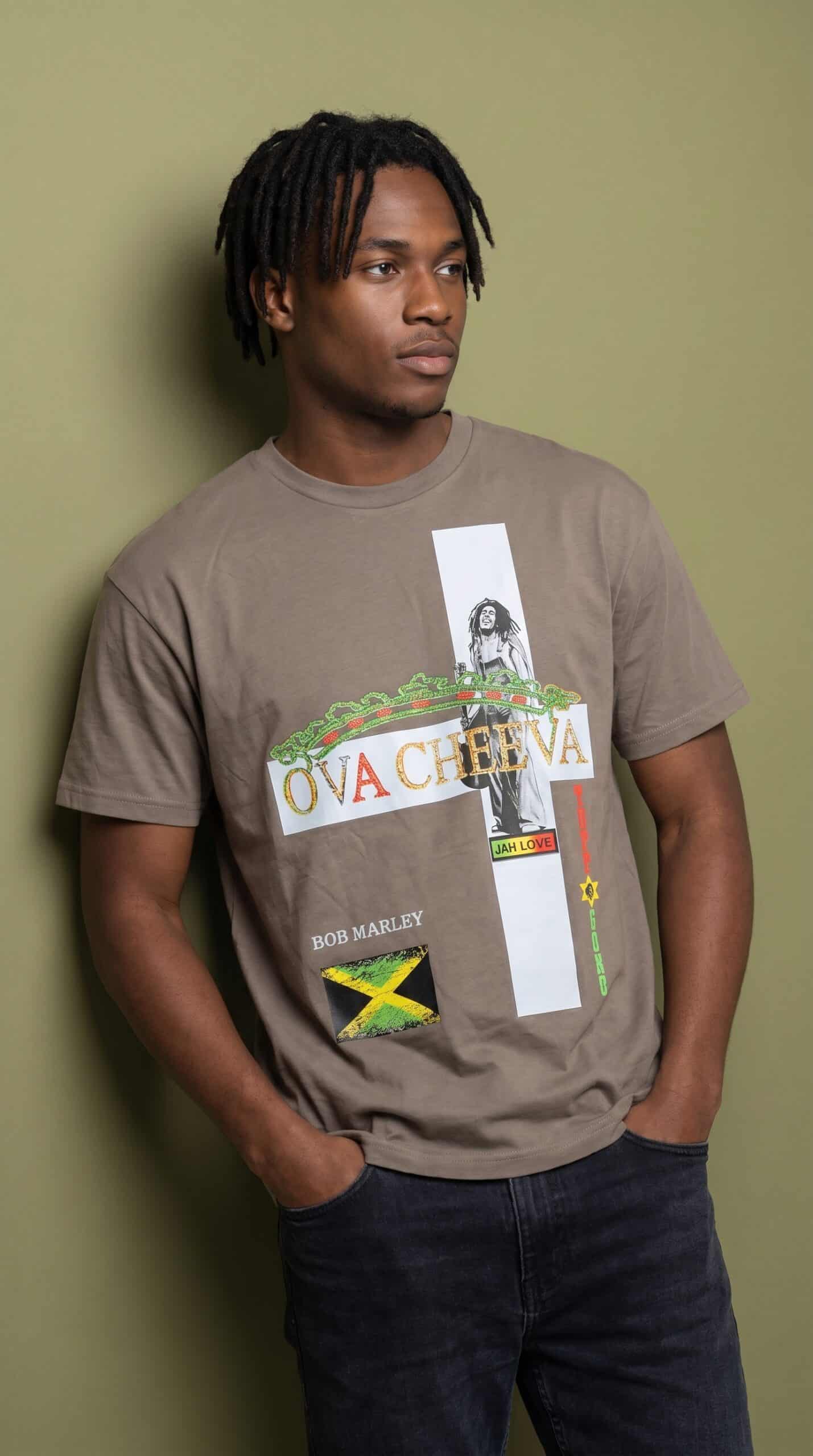 Young man wearing a graphic T-shirt with reggae and Jamaican flag design against a green background.