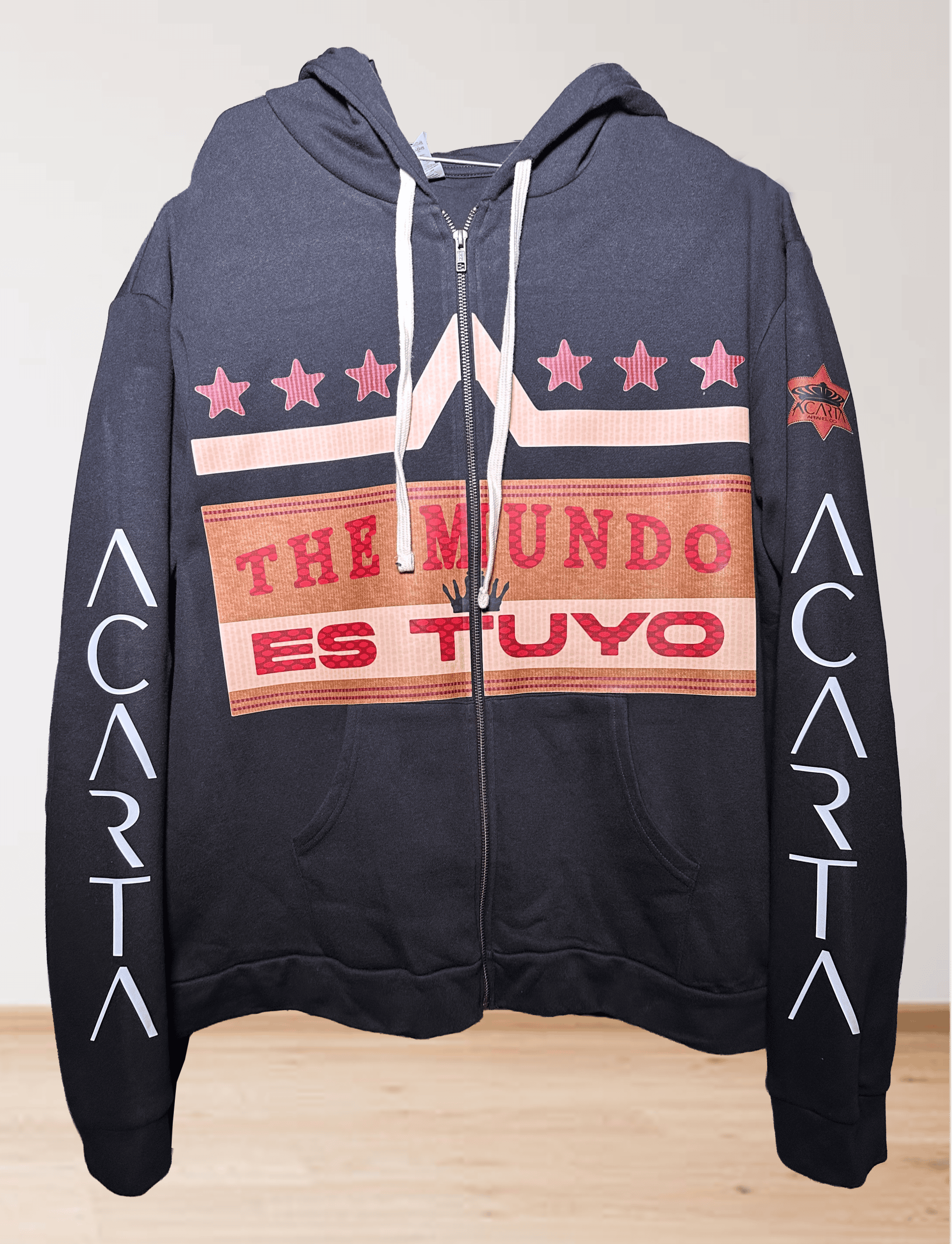 Black hoodie with "THE MUNDO ES TUYO" text and star designs on front.
