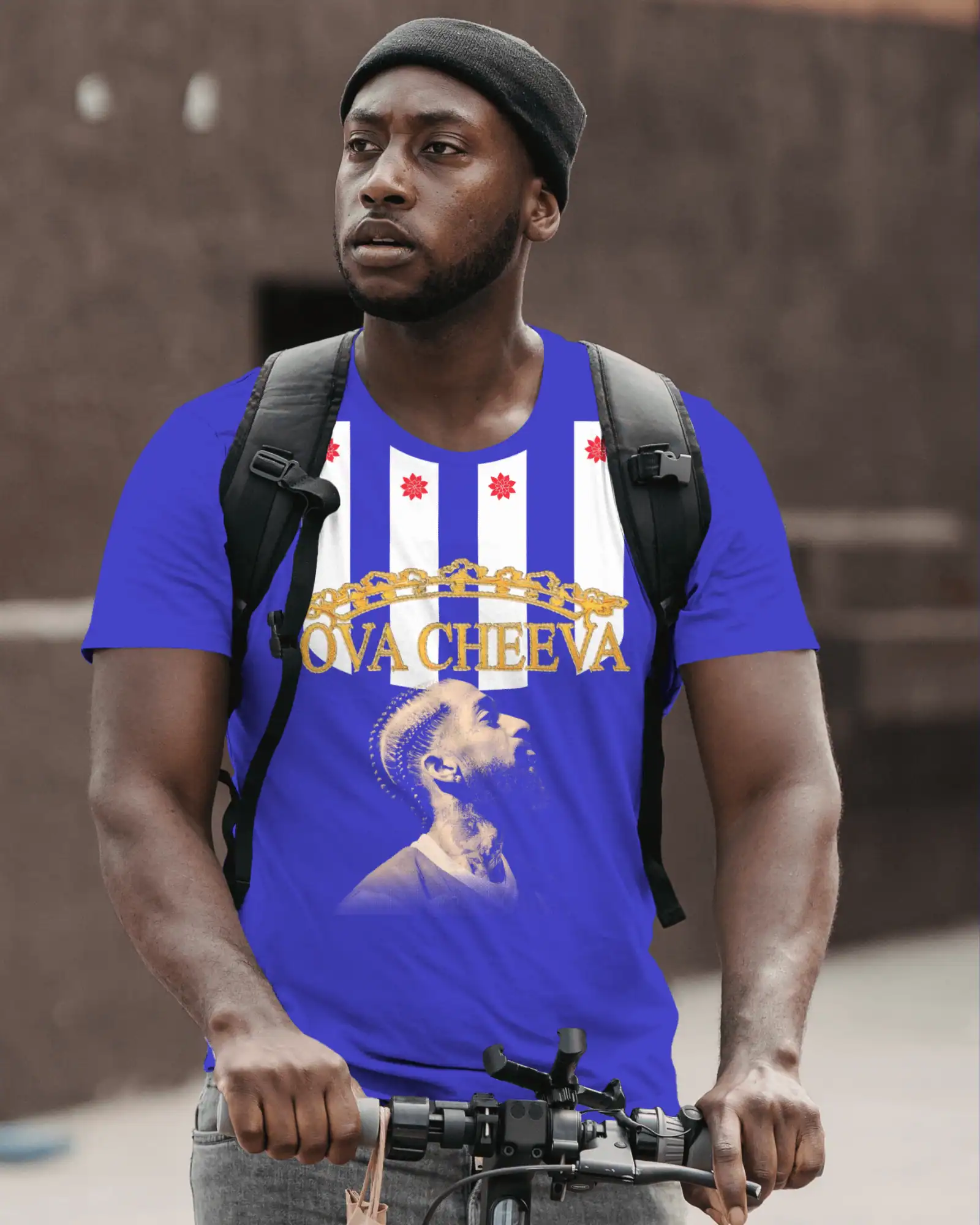 Man in blue graphic t-shirt with backpack, holding bicycle handlebars outdoors.