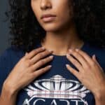 A woman with curly hair wearing a Too Dapper urban apparel t-shirt.